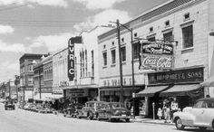 an old black and white photo of cars driving down the street