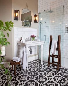 a white sink sitting next to a walk in shower under two mirrors on the wall