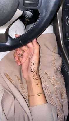 a woman with a tattoo on her arm holding a steering wheel