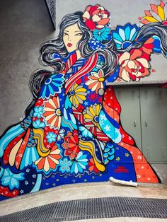 a woman painted on the side of a building with flowers in her hair and flowing hair