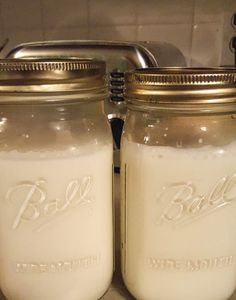 two mason jars sitting on top of a counter next to each other, one filled with liquid and the other empty