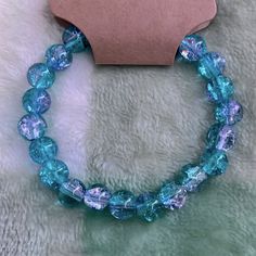 a bracelet with blue glass beads is on a white furnishing next to a tag