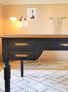 a black desk with two drawers on it in a living room next to a white rug