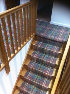 a stair case with plaid carpet and wooden handrails