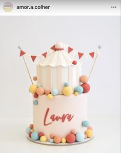 a birthday cake decorated with colorful candies and a circus tent topper that says love