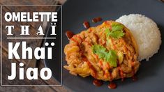 a black plate topped with rice and meat covered in sauce next to a wooden table