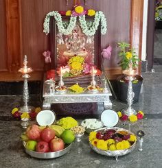 there are many fruits on the table and candles in front of them with buddha statues