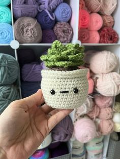 a crochet potted plant with a green leaf on it in front of yarn balls