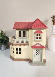 a doll house sitting on top of a table next to a vase and potted plant