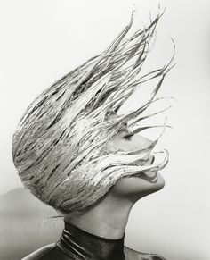 a black and white photo of a woman's head with hair blowing in the wind