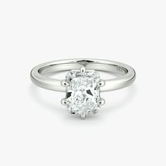 a cushion cut diamond engagement ring on a white background with the center stone set in 18k white gold