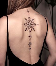 the back of a woman's neck with a snowflake tattoo on it