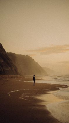 a person standing on top of a beach next to the ocean