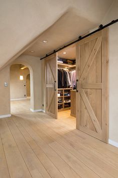 an open closet with wooden floors and sliding doors on the inside, leading to another room