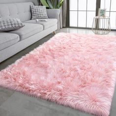 a living room with a white couch and pink rug on the floor in front of a window