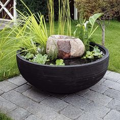 a black planter filled with lots of plants and rocks