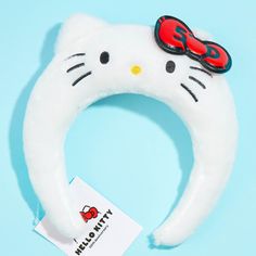 a hello kitty headband with a red bow on it's side and a name tag attached to it