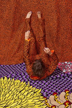 a woman laying on top of a bed covered in an animal print blanket next to a wall