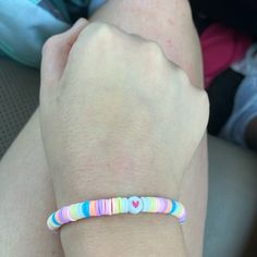 a person wearing a colorful bracelet with hearts on it's end and one hand