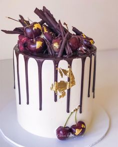 a white cake topped with cherries and chocolate drizzle