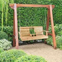 a wooden swing in the middle of a garden