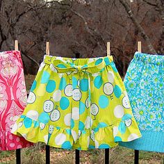 three different colored skirts hanging on clothes pins