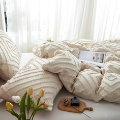 a bed with white pillows and flowers on top of it next to a wooden cutting board