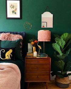 a bedroom with green walls and pink accents on the nightstand next to it is a bed