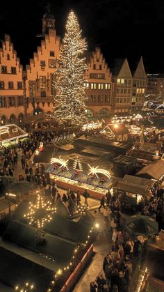 a large christmas tree is lit up in the middle of an outdoor market