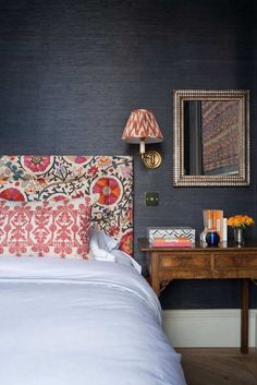 a bedroom with blue walls and white bedding has an orange patterned headboard on it