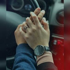 a person holding their hand on the steering wheel of a car while wearing a watch