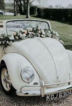 a white vw beetle with flowers on the front