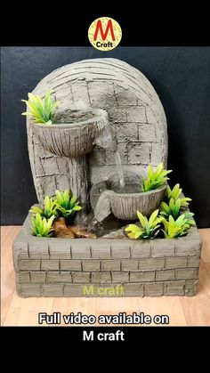 a small fountain made out of bricks with plants in the middle and water running from it