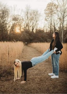 two women are standing in the middle of a field and one is holding another woman's leg