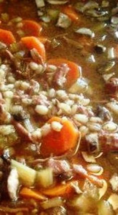 a stew with carrots, onions and meat in a pot on the stove top