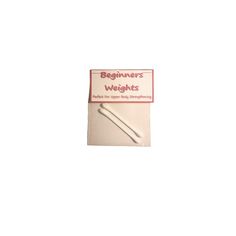 a pair of knitting needles sitting on top of a white cloth covered book with the words beginner's weights written in red