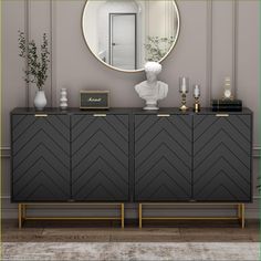 a black and gold sideboard with a round mirror above it on the wall next to a vase