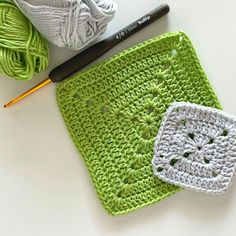 a crochet square and ball of yarn next to each other on a table