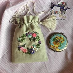 a small bag with flowers on it next to a sewing needle and a pin cushion