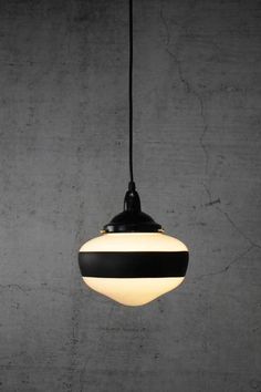 a black and white striped light hanging from a ceiling fixture in a concrete wall background