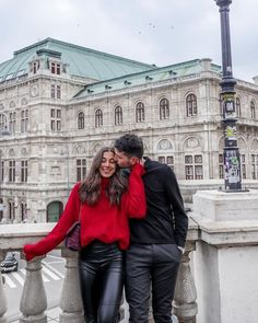 a man and woman standing next to each other in front of a building