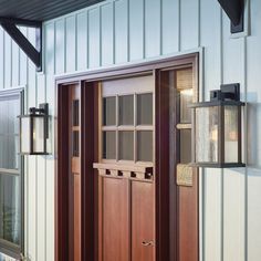 a wooden door with two lanterns on the side of it next to a white building