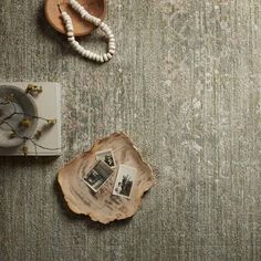 a wood slice on the floor next to a wooden bowl with photos hanging from it