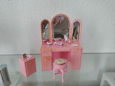 a pink vanity with mirror and stool on display