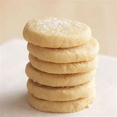 a stack of sugar cookies sitting on top of a white tablecloth next to a glass of milk