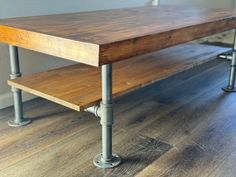 a wooden table sitting on top of a hard wood floor next to metal pipe legs