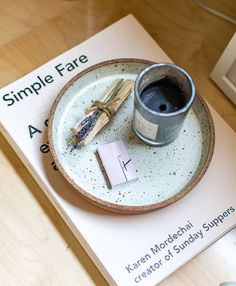 a small plate with a candle and matches on it next to a book about simple fate