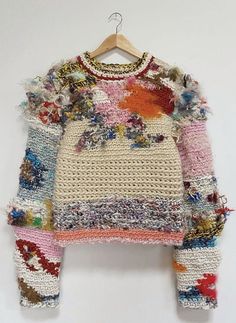 an old sweater is hanging on a hanger and it's made out of crochet