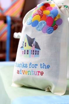 there is a small bag that says thanks for the adventure with balloons on it and a house in the background