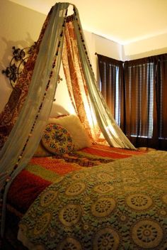 a bed with a canopy over it in a bedroom next to a window and curtains